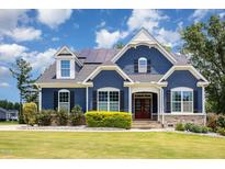 Charming two-story home featuring a blue exterior, stone accents, a well-manicured lawn, and solar panels at 119 Florentino Ct, Clayton, NC 27527