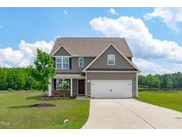 Inviting two-story home featuring a two-car garage, well-manicured lawn, and a charming covered front porch at 124 Lahinch Dr, Fuquay Varina, NC 27526