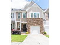 Charming townhome featuring a stone facade, attached garage, and a well-manicured lawn at 1402 Southpoint Trl, Durham, NC 27713