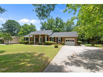 Charming brick home featuring a manicured lawn, mature trees, and a welcoming front porch at 1601 Redmond Dr, Durham, NC 27712