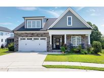 Charming home featuring a stone facade, white garage door and manicured front lawn at 1918 Morning Fog Dr, Fuquay Varina, NC 27526