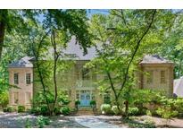 Stunning brick home with mature trees and a charming blue double-door entrance with wreath adornments at 2602 Vintage Hill Ct, Durham, NC 27712