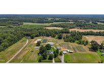 Expansive aerial view of a lush farm featuring fields, ponds, farm buildings, and a charming residence at 2856 Gwyn Rd, Elon, NC 27244