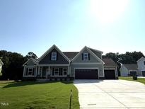 Charming two-story home with gray siding, a three-car garage and a well-manicured lawn at 290 Busterfield Ct, Benson, NC 27504