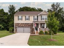 Two-story home with stone and siding, attached two-car garage, green lawn, and neatly trimmed shrubs at 3292 Longpine Rd, Burlington, NC 27215