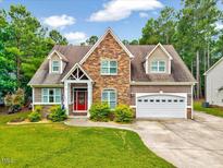 Charming home with stone accents, manicured lawn, red front door, and an attached two-car garage at 39 Westover Ct, Sanford, NC 27332