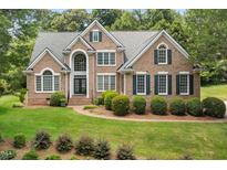 Traditional brick home featuring a manicured lawn, lush landscaping and eye-catching architectural details at 402 Bridewell Ct, Cary, NC 27518