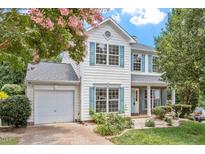 Charming two-story home with light colored siding, blue shutters, attached garage and mature landscaping at 404 Ascott Way, Durham, NC 27713