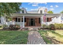 Charming brick home featuring a welcoming front porch with white railings and an American flag at 412 Coggeshall St, Oxford, NC 27565