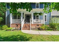 Charming blue home featuring a welcoming front porch with brick stairs and manicured landscaping at 4151 Deep Wood Cir, Durham, NC 27707