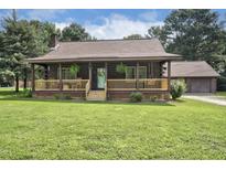 Charming log cabin with a cozy front porch, lush lawn, and a detached garage at 5593 Leon Rd, Nashville, NC 27856