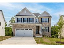 Beautiful two-story brick home with attached two car garage and a well-manicured lawn on a sunny day at 57 Blanton Ct, Lillington, NC 27546