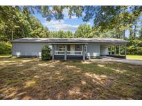 Charming single-story home with a cozy front porch and an attached carport, surrounded by mature trees at 7595 Clayton Blvd # B, Clayton, NC 27520