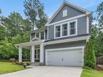 Charming two-story home featuring gray siding, white trim, and a two-car garage with a well-manicured front lawn at 128 Chapel Run Way, Chapel Hill, NC 27517