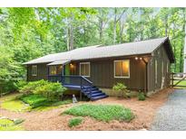 Charming exterior view of home with lush landscaping, wood siding, and a blue painted porch and trim at 1403 Meadow Ln, Chapel Hill, NC 27516