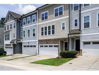 Charming townhome exterior featuring a two-car garage, brick accents, and manicured lawn at 1434 Salem Dr, Apex, NC 27502