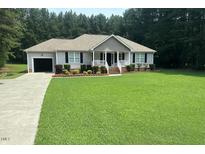 Charming single-story home with a manicured lawn, inviting porch, and attached garage at 1515 Bradsher Dr, Stem, NC 27581