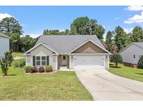 Charming single-story home with a well-manicured lawn and two-car garage, complemented by mature trees at 21 Cambridge Dr, Angier, NC 27501