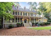 Two-story home with a welcoming front porch, complemented by lush landscaping and mature trees at 3025 Bentwillow Dr, Fuquay Varina, NC 27526