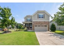 Charming two-story home features a stone facade, manicured lawn, and attached two-car garage at 3601 Lily Orchard Way, Apex, NC 27539