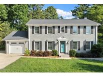 Charming two-story brick home with a manicured lawn, gray roof, black shutters, and a delightful blue front door at 5509 Cliffwood Ct, Raleigh, NC 27609