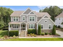 Charming two-story home with stone accents, manicured landscaping, and welcoming front porch at 7410 Chouder Ln, Wake Forest, NC 27587