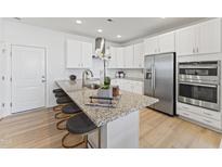 Modern kitchen features white cabinets, stainless steel appliances, and a granite-topped island with bar stool seating at 915 Ball Field Aly # 101, Cary, NC 27511