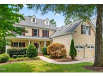 Charming two-story yellow home with a well-manicured lawn, mature trees, and inviting front porch at 11124 Penderwood Ct, Raleigh, NC 27617