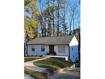 Charming one-story home with a white painted brick exterior, landscaped yard, and a walkway leading to the front entrance at 1128 E Geer St, Durham, NC 27704