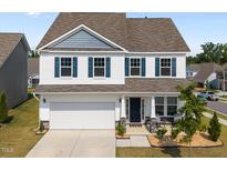 Charming two-story home featuring white siding, blue shutters, a two-car garage, and a welcoming front porch at 14 Shady Oaks Rd, Angier, NC 27501