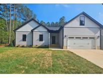 Charming one-story home with attached garage, landscaped yard, and inviting front porch at 1414 Sagamore Dr, Louisburg, NC 27549