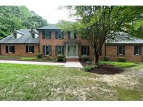 Inviting brick home with mature trees, manicured shrubs, and pathway leading to the front door at 14236 Wyndfield Cir, Raleigh, NC 27615