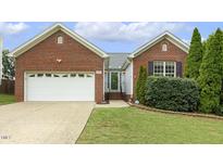 Charming brick home featuring an attached garage, well-maintained lawn, and manicured landscaping at 2012 Summer Shire Way, Raleigh, NC 27604