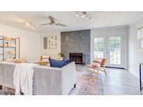 Bright living room featuring a stone fireplace, ceiling fan, stylish furniture, and access to outdoor space at 2014 Athens Ave, Durham, NC 27707