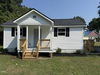 Charming white home featuring black shutters and a wooden porch with well-maintained landscaping at 203 Hope St, Erwin, NC 28339
