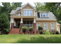 Inviting two-story home with a charming front porch and well-manicured lawn at 221 Grantwood Dr, Holly Springs, NC 27540