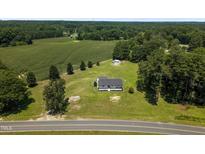 Aerial view of a charming country home with a large yard surrounded by green fields and mature trees at 224 Grameta Ln, Lillington, NC 27546