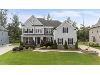 A charming two-story home with gray siding, black shutters, and a beautifully landscaped front yard at 228 Cloverdale Rd, Apex, NC 27523