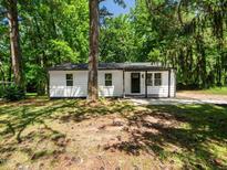 Charming single-story home featuring white siding, a black door and trim, and mature trees surrounding the property at 4428 W West River Rd, Franklinton, NC 27525