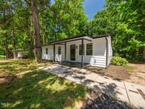 Charming single story home with light colored siding, dark trim, and inviting front porch nestled amongst mature trees at 4428 W West River Rd, Franklinton, NC 27525