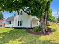 Charming two-story home with white siding, black shutters, and a well-maintained lawn and landscaped garden at 510 May St, Gibsonville, NC 27249