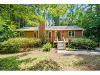 Charming single-story home with wood siding and a cozy front porch surrounded by mature trees and lush landscaping at 601 Wofford Rd, Durham, NC 27707