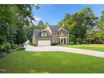 Traditional brick two-story home featuring an attached two-car garage and lush landscaping at 7713 Summercrest Dr, Apex, NC 27539