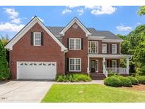 Charming two-story brick home featuring a manicured lawn and attached two-car garage at 1153 Litchborough Way, Wake Forest, NC 27587