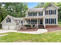 Traditional two-story home featuring neutral siding, dark shutters, covered porch, and mature landscaping at 11619 Appaloosa W Run, Raleigh, NC 27613