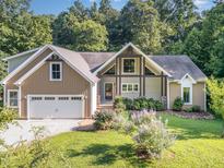 Charming exterior of home with manicured lawn, flowering bushes, two-car garage and beautiful architectural features at 136 Vireo Ln, Hillsborough, NC 27278