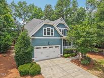 Charming blue two-story home featuring a two-car garage, manicured landscaping, and a welcoming front porch at 1419 Endgame Ct, Wake Forest, NC 27587