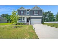 Inviting two-story home with a well-manicured lawn and a charming front porch at 1505 Willow Landing Way, Willow Springs, NC 27592