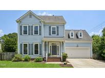 Charming two-story home with light blue siding, gray shutters, and a well-manicured front lawn at 1818 Misty Hollow Ln, Apex, NC 27502