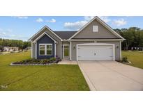 Charming single-story home with gray siding, a two-car garage and a well-manicured lawn with flower beds at 19 Linda Lou Ln # 19, Angier, NC 27501